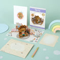 Load image into Gallery viewer, Image of Cardology New Baby Bear Pop Up Card which is also perfect as a first birthday card and gift. Image shows card fully open with the reversible envelope, the card front cover, packaging and slide out notecard