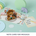 Load image into Gallery viewer, Image of Cardology New Baby Bear Pop Up Card which highlights the slide out notecard which is a space for you to write your personal message without ruining the aesthetic of the card