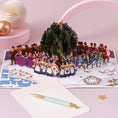 Load image into Gallery viewer, Twelve Days of Christmas Pop Up Card - Partridge in a Pear Tree 3D Christmas Card - lifestyle image of the card open with a notecard and pen