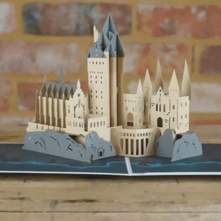 A 3D pop-up card depicting Hogwarts Castle from the Harry Potter series, displayed against a wooden table background.
