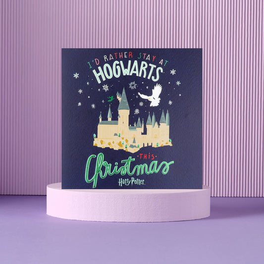 Blue Harry Potter Christmas Card which reads 'I'd Rather Stay At Hogwarts This Christmas' - image taken on a purple lifestyle backdrop