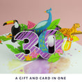 Load image into Gallery viewer, lifestyle of image of the bold and colourful 30th birthday pop up card for her on a pink background
