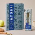 Load image into Gallery viewer, A Battersea A5-lined notebook in a dusty blue tone with black dog doodle illustrations
