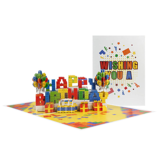 Birthday Bricks Pop Up Card for kids and adults who like building.  Image of the pop up card  open with the card front cover behind it, which spells out Happy Birthday in colourful bricks with balloons either side.