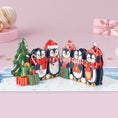 Load image into Gallery viewer, Open Penguin pop-up Christmas card featuring a 3D penguin in a snowy winter scene, holding a present next to a miniature Christmas tree
