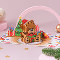 Load image into Gallery viewer, Cute teddy bear pop-up Christmas card, opened up to reveal a 3D teddy in a Santa hat sitting among wrapped gifts.
