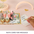 Load image into Gallery viewer, lifestyle image of the celebratory love pop up card notecard which gives a space to write your personal message without ruining the aesthetic of the card pop up - by Cardology
