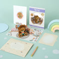 Load image into Gallery viewer, Image of Cardology New Baby Bear Pop Up Card which is also perfect as a first birthday card and gift. Image shows card fully open with the reversible envelope, the card front cover, packaging and slide out notecard
