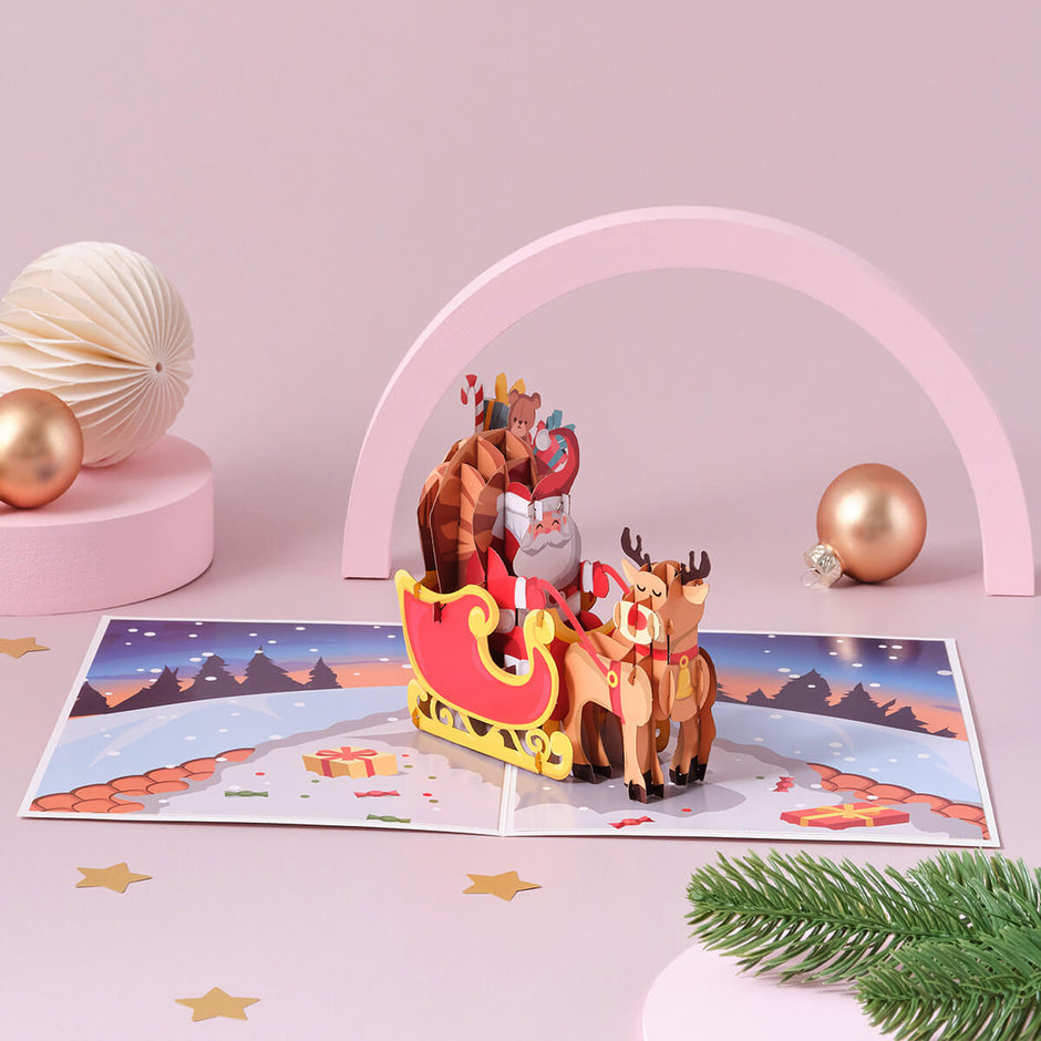 Santa Sleigh Christmas Pop Up Card with Rudolf the rednose reindeer - christmas cards - lifestyle image of card open with baubles, and decorations