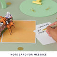 Load image into Gallery viewer, Show jumping pop up card by Cardology - lifestyle image of slide out notecard which gives a place to write your message
