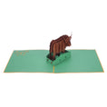 Load image into Gallery viewer, Highland Cow Pop Up Card featuring a 3D bronze highland cow standing among green grass, fully open
