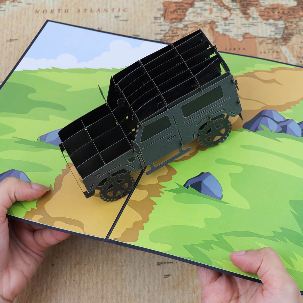 Image showing a pair of hands holding the landrover pop up card open with a map background